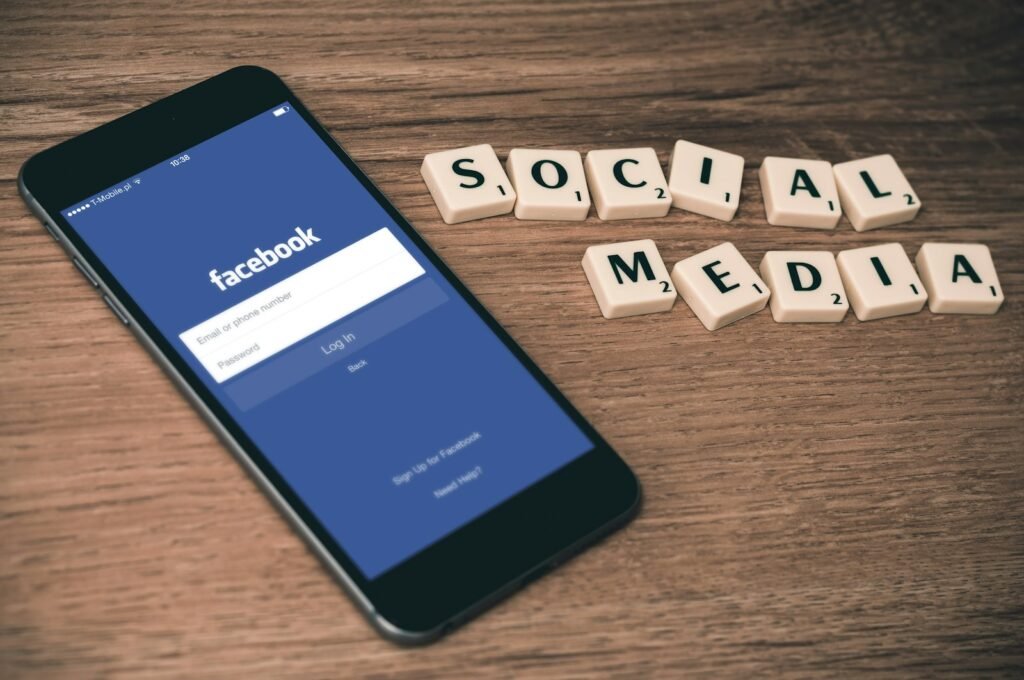 Facebook app on a phone next to letter tiles spelling social media
